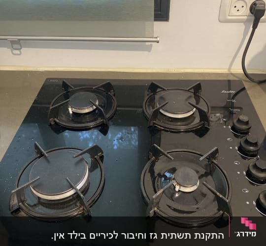 כיריים גז שחורות עם ארבעה מבערים וכפתורי שליטה